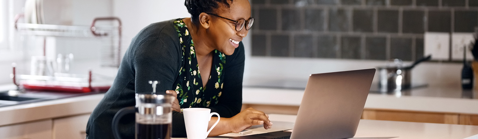 a woman in her kitchen looking on her laptop