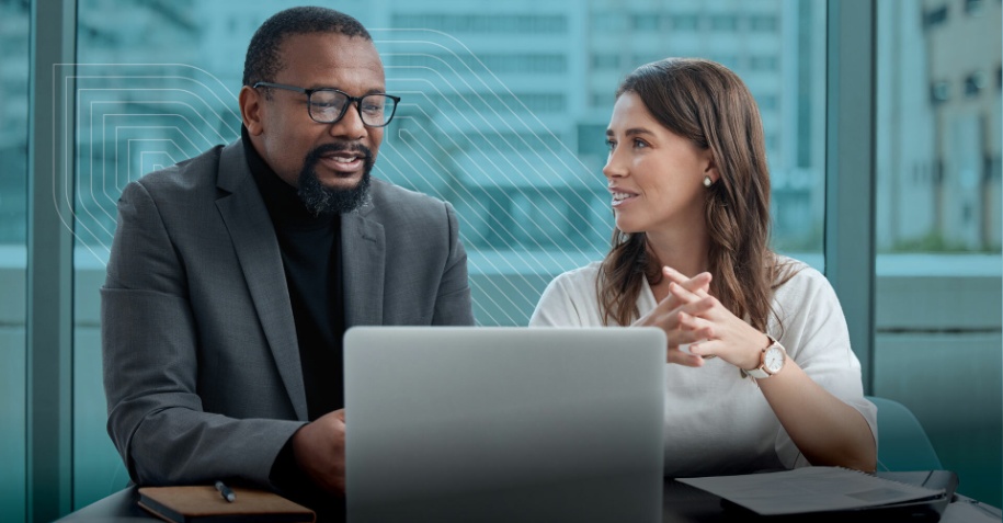 two people talking while sitting in front of a laptop computer